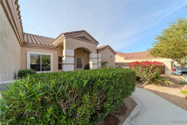 exterior space with a tile roof and stucco siding