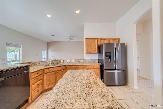 kitchen featuring light stone counters, stainless steel refrigerator with ice dispenser, light tile patterned flooring, a sink, and dishwasher