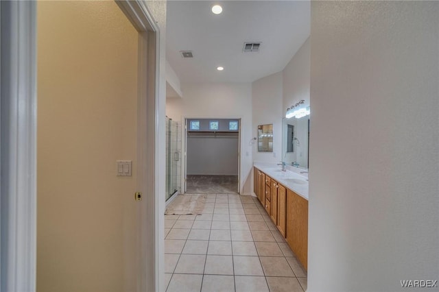 full bath with a stall shower, tile patterned floors, visible vents, and double vanity