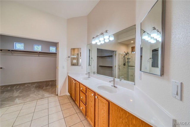 bathroom featuring a walk in closet, double vanity, a sink, and tile patterned floors