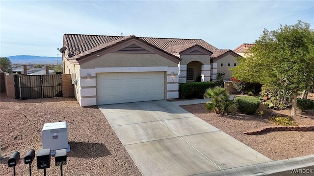 mediterranean / spanish house with driveway, a tile roof, an attached garage, a mountain view, and stucco siding