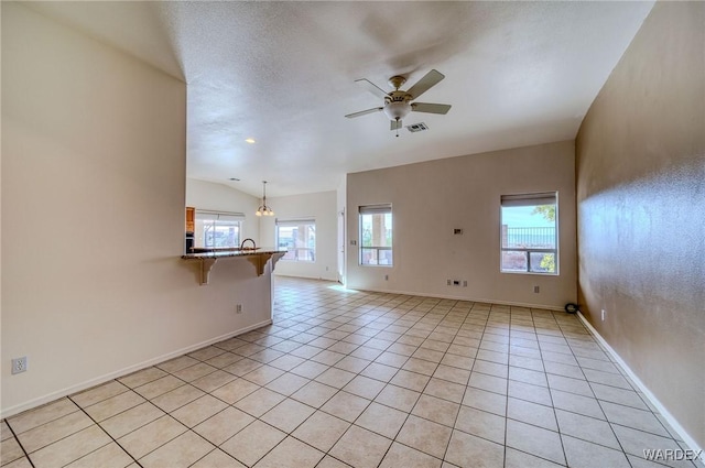 empty room featuring light tile patterned floors, lofted ceiling, visible vents, ceiling fan, and baseboards