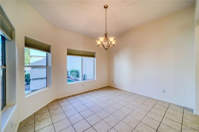 spare room with light tile patterned flooring, baseboards, and an inviting chandelier