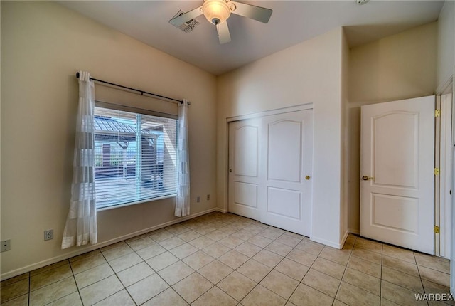 unfurnished bedroom with light tile patterned floors, a closet, visible vents, ceiling fan, and baseboards