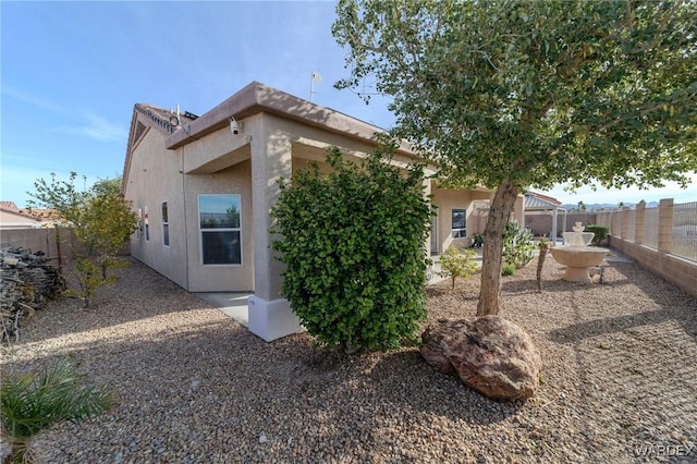 rear view of property with a fenced backyard and stucco siding