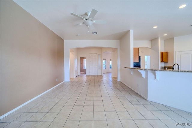 unfurnished living room with light tile patterned floors, visible vents, arched walkways, ceiling fan, and recessed lighting