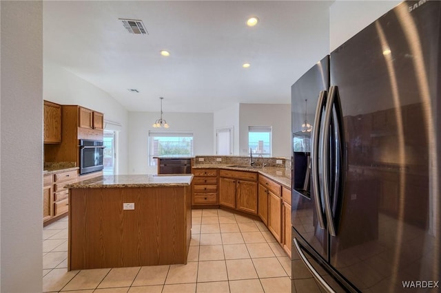 kitchen featuring visible vents, appliances with stainless steel finishes, a center island, hanging light fixtures, and a sink