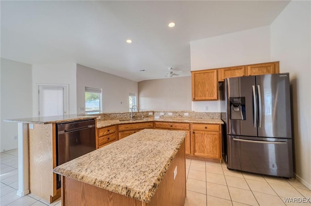 kitchen featuring a center island, light tile patterned floors, brown cabinetry, a sink, and stainless steel fridge