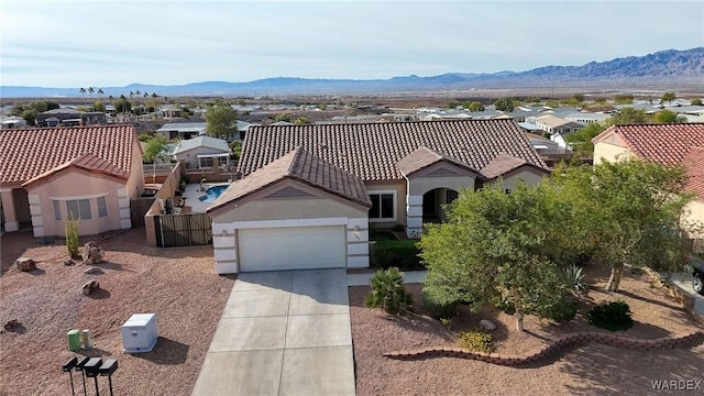 mediterranean / spanish house with an attached garage, a mountain view, driveway, a tiled roof, and a residential view