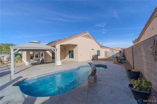 back of house featuring a fenced in pool, a patio, stucco siding, a gazebo, and a fenced backyard