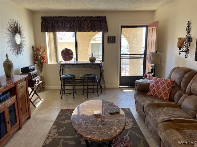 living room featuring a textured ceiling, light tile patterned floors, and a healthy amount of sunlight