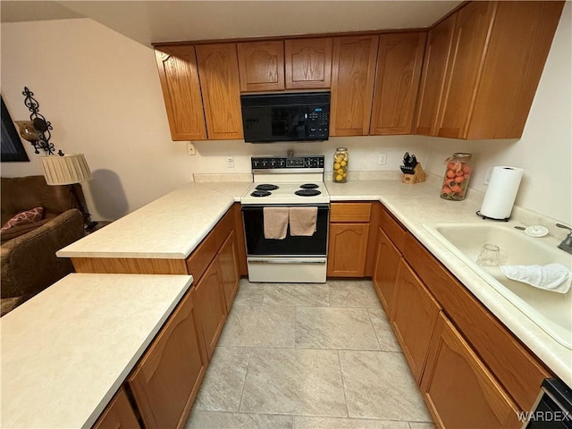 kitchen with brown cabinets, electric range, black microwave, and light countertops