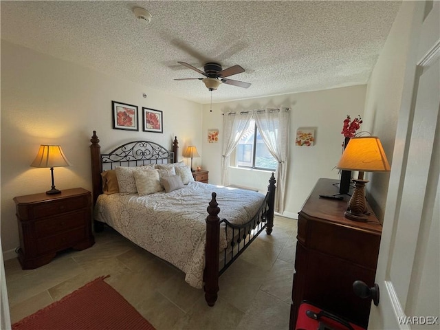 bedroom featuring ceiling fan, a textured ceiling, and baseboards