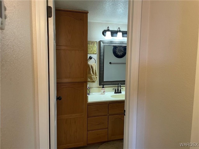 bathroom with a textured wall, vanity, and a textured ceiling