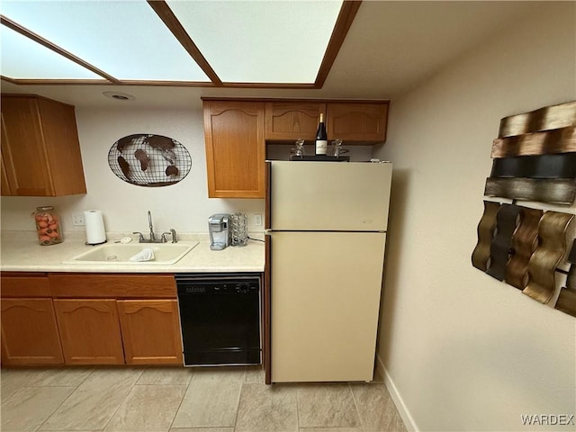 kitchen with dishwasher, light countertops, a sink, and freestanding refrigerator