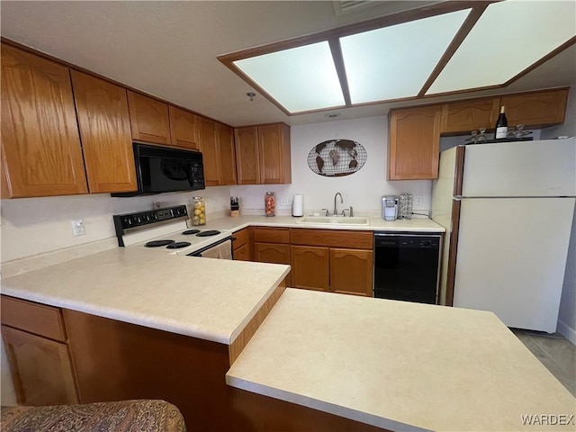 kitchen with brown cabinets, light countertops, a sink, a peninsula, and black appliances