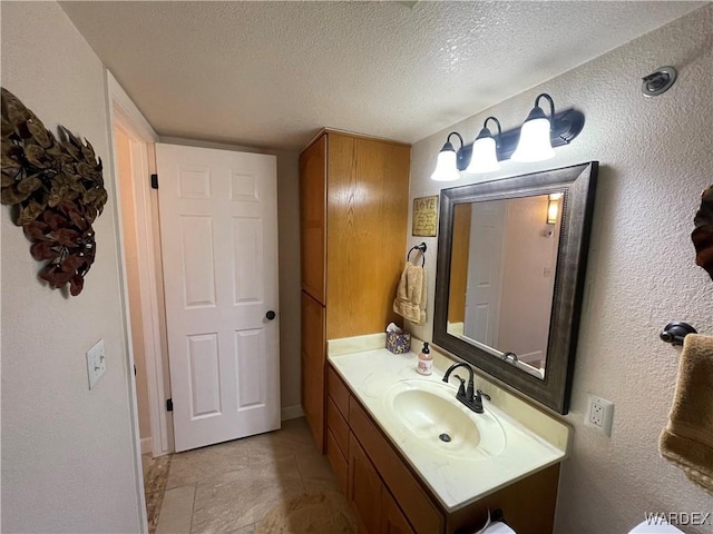 bathroom with a textured ceiling, a textured wall, and vanity