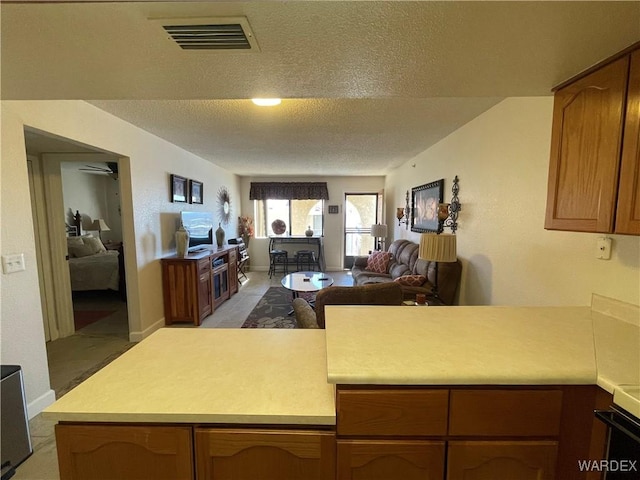 kitchen with brown cabinets, light countertops, visible vents, and a peninsula