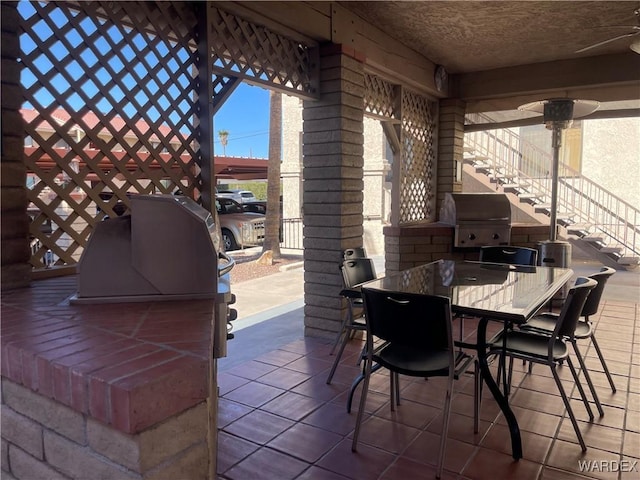 view of patio with exterior kitchen, outdoor dining space, grilling area, and stairs