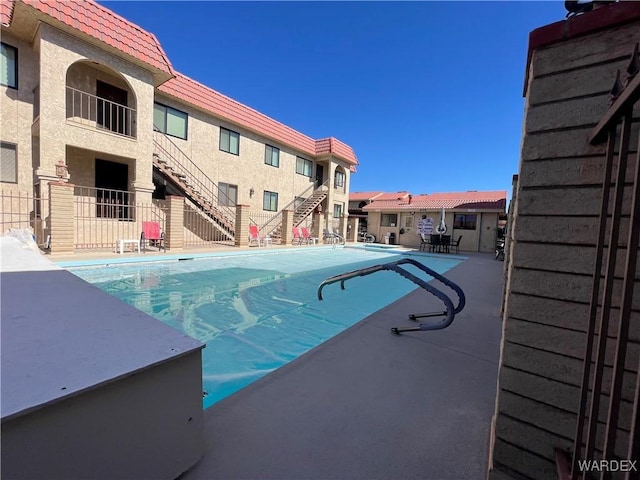 community pool with fence, stairway, and a patio