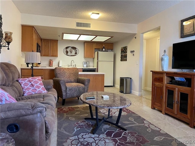 living area with visible vents, a textured ceiling, and baseboards