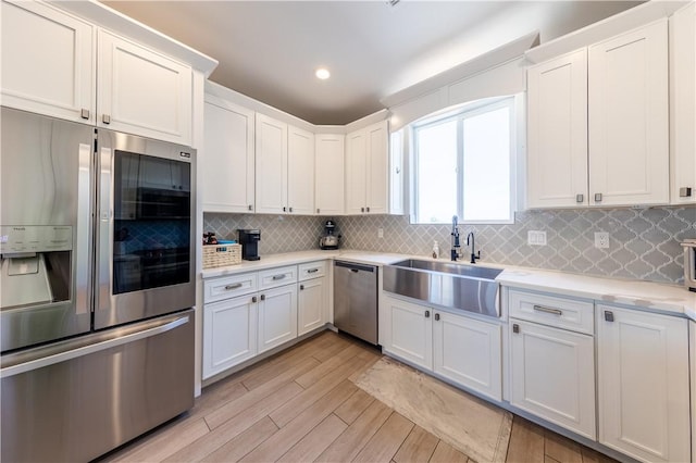 2178 E Via Lucio, Fort Mohave, AZ 86426 - kitchen with appliances with stainless steel finishes, a sink, light countertops, light wood finished floors, and decorative backsplash