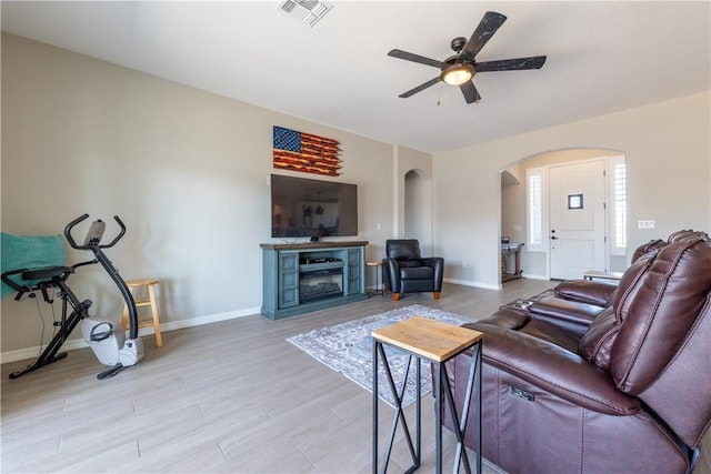 2178 E Via Lucio, Fort Mohave, AZ 86426 - living room featuring arched walkways, a ceiling fan, light wood finished floors, baseboards, and a fireplace