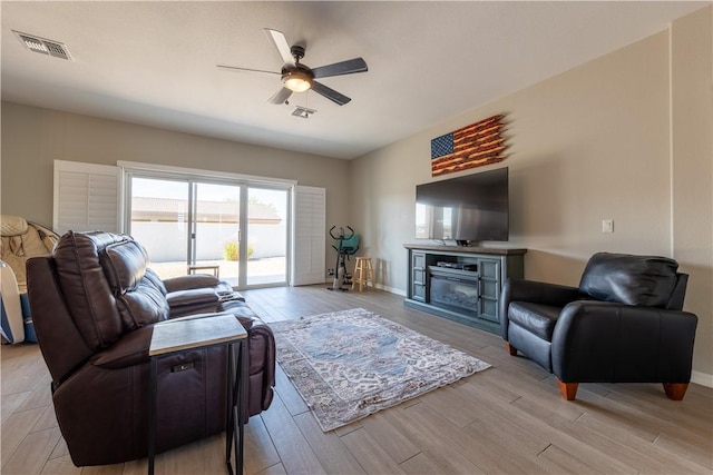 2178 E Via Lucio, Fort Mohave, AZ 86426 - living room featuring a ceiling fan, light wood finished floors, a glass covered fireplace, and baseboards