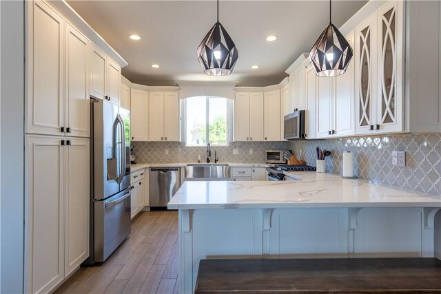 2178 E Via Lucio, Fort Mohave, AZ 86426 - kitchen featuring appliances with stainless steel finishes, a sink, a peninsula, light wood-style flooring, and tasteful backsplash