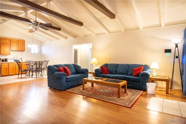 living area featuring vaulted ceiling with beams, light wood finished floors, and ceiling fan with notable chandelier