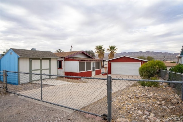 view of front facade with a garage, fence, a mountain view, and an outbuilding