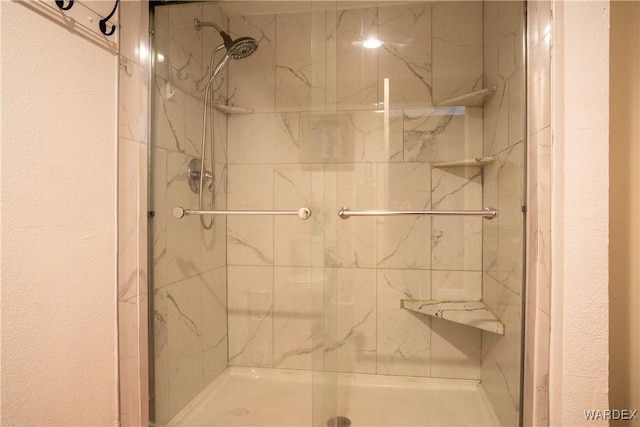 bathroom with a textured wall and a shower stall