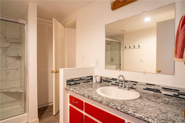 bathroom with a shower stall, backsplash, a closet, and vanity