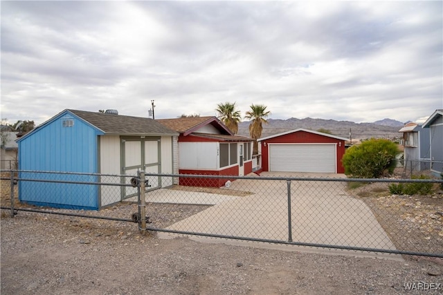 view of front of house featuring fence, a mountain view, and an outbuilding