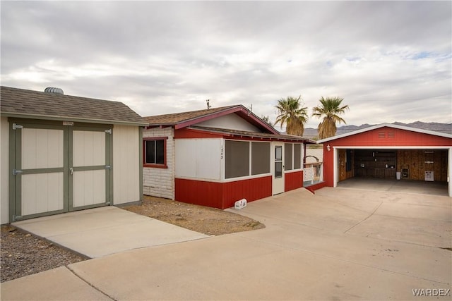 view of front of home with roof with shingles, an outdoor structure, and a detached garage