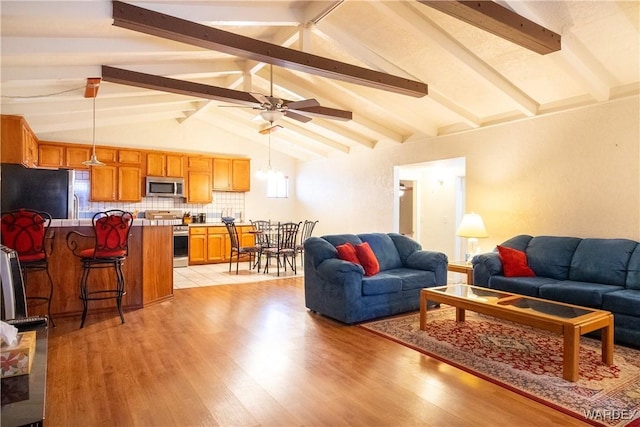 living room featuring vaulted ceiling with beams, light wood-style flooring, and a ceiling fan