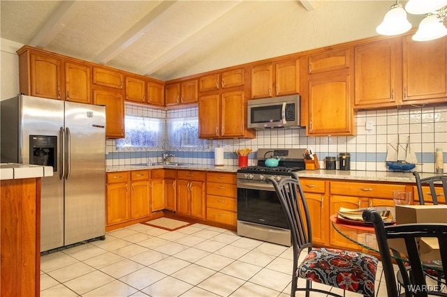 kitchen featuring lofted ceiling with beams, brown cabinetry, stainless steel appliances, and backsplash