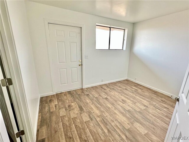 unfurnished room with light wood-type flooring and baseboards