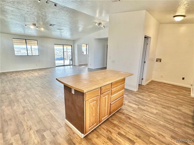 kitchen with light wood finished floors, visible vents, open floor plan, and a textured ceiling