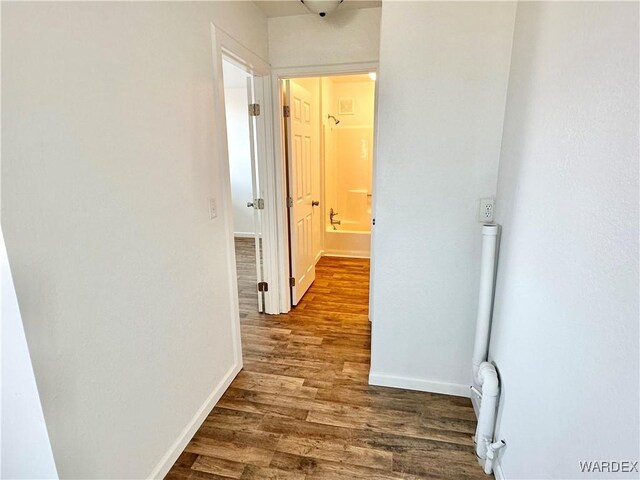 corridor with dark wood finished floors and baseboards