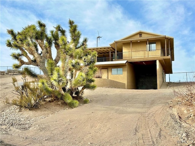 exterior space with a balcony, dirt driveway, and stucco siding