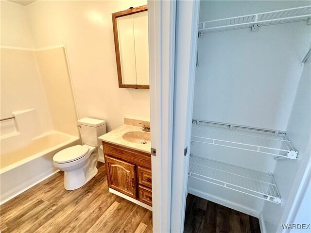 bathroom with shower / bath combination, vanity, toilet, and wood finished floors