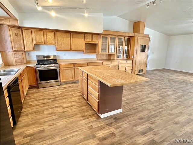 kitchen featuring light wood finished floors, glass insert cabinets, stainless steel gas stove, butcher block countertops, and dishwasher