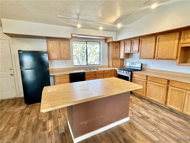 kitchen featuring a kitchen island, a textured ceiling, light wood-type flooring, black appliances, and a sink