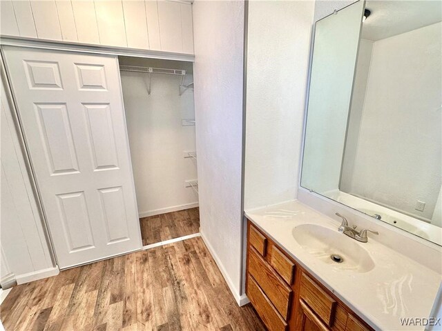 bathroom with baseboards, wood finished floors, and vanity