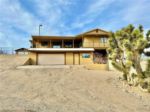 view of front facade with driveway, a balcony, an attached garage, and stucco siding