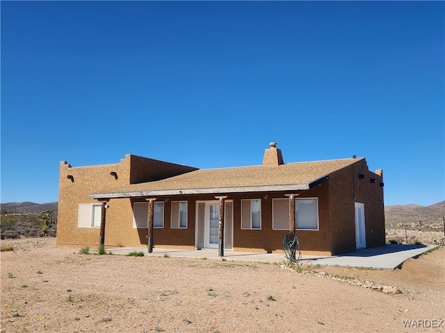 view of front of property with a patio area, a chimney, stucco siding, and a mountain view