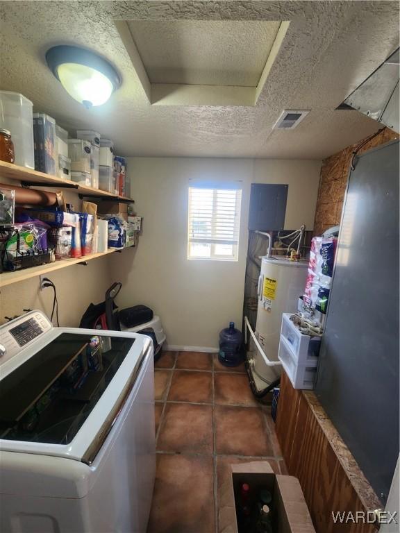 laundry room featuring a textured ceiling, water heater, visible vents, and washer and dryer