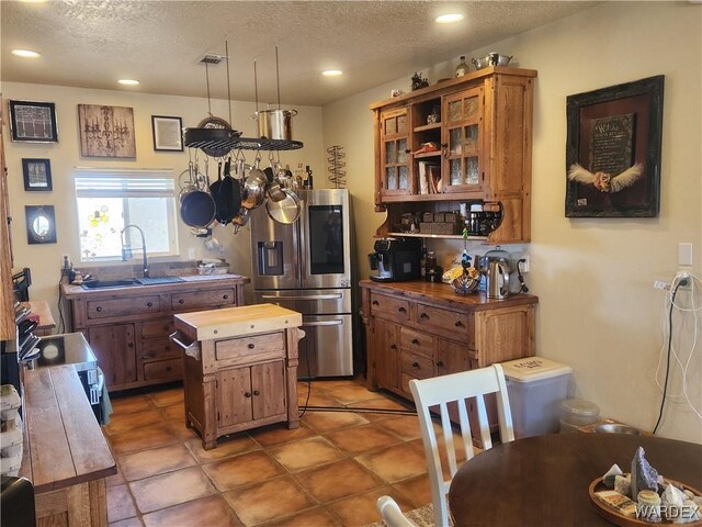 kitchen featuring brown cabinetry, a textured ceiling, stainless steel appliances, and a sink