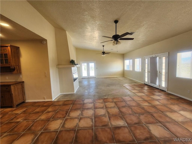 unfurnished living room with vaulted ceiling, a ceiling fan, a textured ceiling, french doors, and baseboards